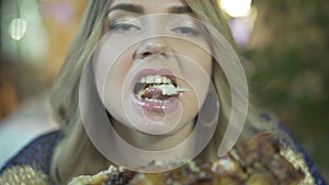Blonde beautiful young greedy woman biting huge pieces of meat eating with hands angry inappropriate in close up shot
