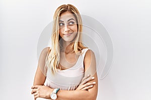 Blonde beautiful young woman standing over white isolated background smiling looking to the side and staring away thinking