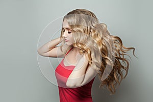 Blonde beauty. Pretty woman with long healthy hair on gray background