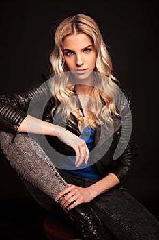 Blonde biker woman in leather jacket resting hand on knee