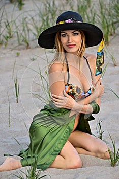 blonde bikini model posing on the beach, wearing colorful swimsuit, silk shirt and hat.