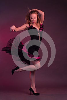 Blonde, in black Spanish Dressdress flamenco dancer in action, on a Burgundy background of the Studio