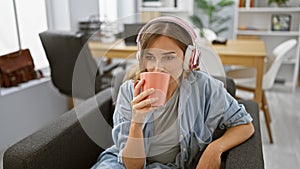 Blonde boss babe alert! a young businesswoman serenading her office with music, while sipping on coffee, hard at work