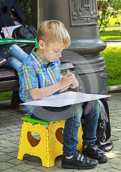 blonde boy learning to draw objects outdoors on plein air