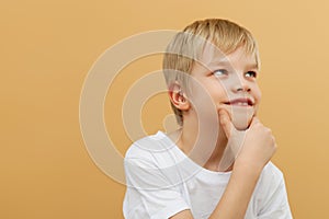 Blonde boy . Let me think . Thoughtful clever schooler in white shirt with puzzled serious expression , child