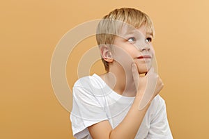 Blonde boy . Let me think . Thoughtful clever schooler in white shirt with puzzled serious expression , child