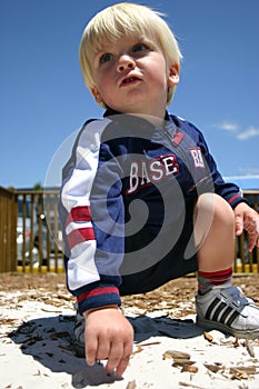 Blonde boy playing in sandy playground