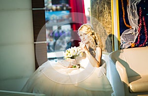 Blonde bride sitting on the armchair in room