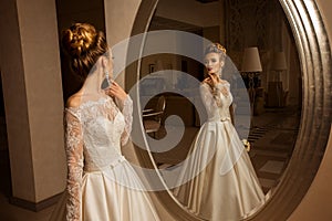 Blonde bride in wedding dress looking at the mirror