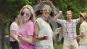 Blonde and brunette girls having fun at summer pool party, dancing with friends