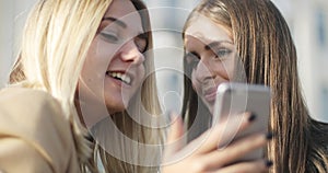 Blonde and brunette smiling and laughing. Close up faces.