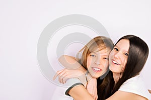 Blonde and brunette teen girls cuddling and laughi