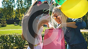 Blonde and brunette young women in colorful clothes with birthday hats. Friends hugging