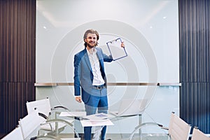 Blonde business man holding blank paper on blank glass board