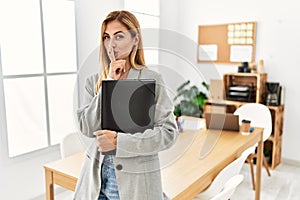 Blonde business woman at the office asking to be quiet with finger on lips