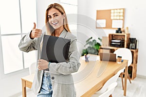 Blonde business woman at the office doing happy thumbs up gesture with hand