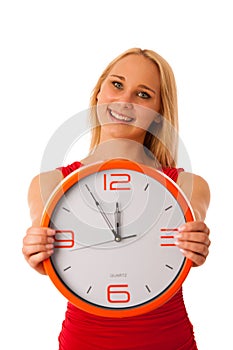 Blonde business woman in red shirt holds clock as sign for time