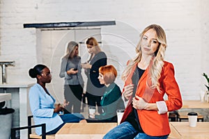 Blonde business woman smiling at camera with colleagues working in background