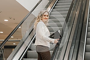 Blonde Businesswoman Using Escalator In Modern City. business woman goes up the escalator