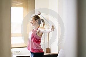 Blonde caucasian athlete woman doing exercises with elastic band in living room at home