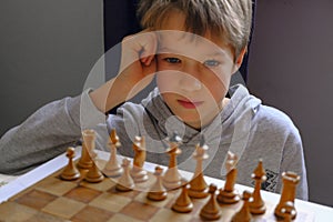 Blonde caucasian boy thinking of a next chess move Playing chess. Strategy, planning concept