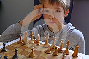 Blonde caucasian boy thinking of a next chess move  Playing chess. Strategy, planning concept