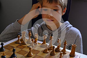 Blonde caucasian boy thinking of a next chess move Playing chess. Strategy, planning concept