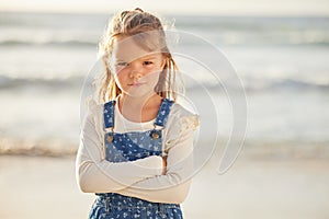 Blonde caucasian little girl with folded arms looking angry, annoyed and stubborn while spending a summer day at the