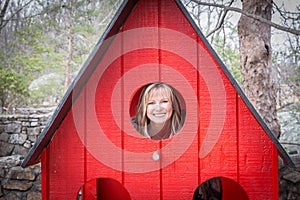 Blonde caucasian woman peaking through a small window.