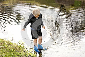 Blonde child trying to catch some fish with a hand net