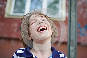 Blonde curly-haired boy cheerfully laughs