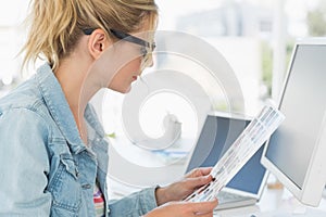 Blonde editor looking at contact sheet at her desk