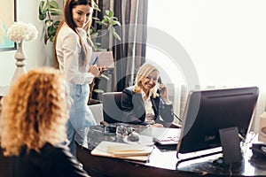 Blonde executive businesswoman doing multitasking work in office.