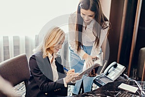 Blonde executive businesswoman doing multitasking work in office.