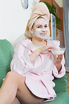 Blonde with face pack relaxing on sofa indoors