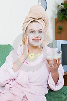 Blonde with face pack relaxing on sofa indoors