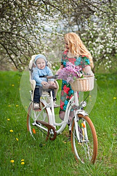 Blonde female with city bicycle with baby in bicycle chair