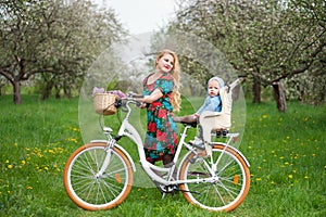 Blonde female with city bicycle with baby in bicycle chair