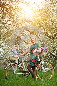 Blonde female with city bicycle with baby in bicycle chair