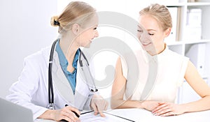 Blonde female doctor and patient talking in hospital office. Health care and client service in medicine