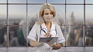 Blonde female doctor typing something on a digital tablet pc device.