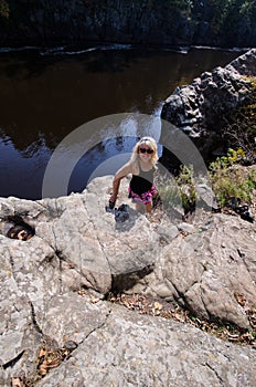 Blonde female hiker stands on a bluff cliff at Interstate State