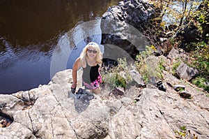 Blonde female hiker stands on a bluff cliff at Interstate State Park