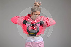 Blonde female in pink hoodie use weights in the gym