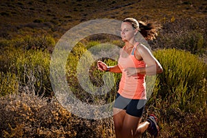 Blonde female trail runner running through a mountain landscape