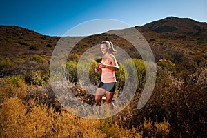 Blonde female trail runner running through a mountain landscape