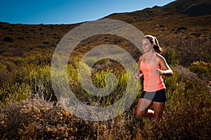 Blonde female trail runner running through a mountain landscape