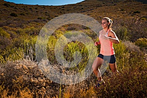 Blonde female trail runner running through a mountain landscape