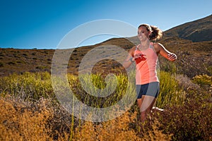 Blonde female trail runner running through a mountain landscape