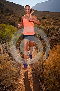 Blonde female trail runner running through a mountain landscape